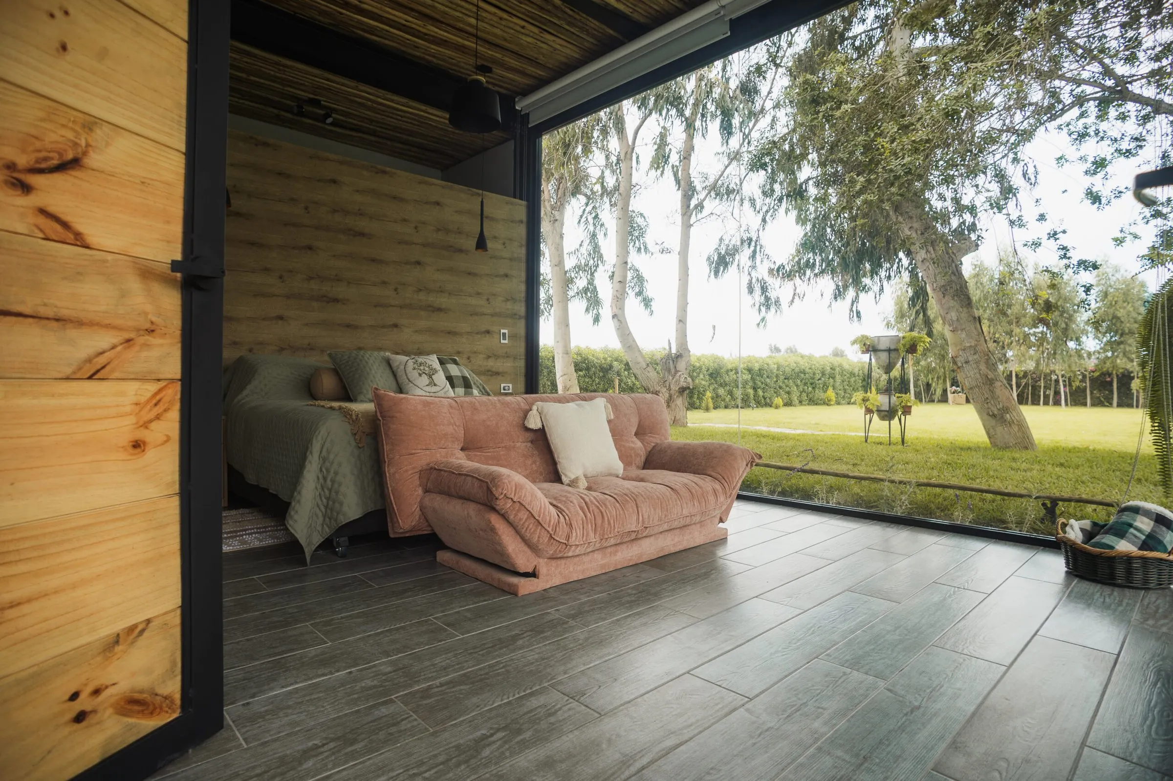 Dormitorio con pared de madera que se abre por completo al jardín.