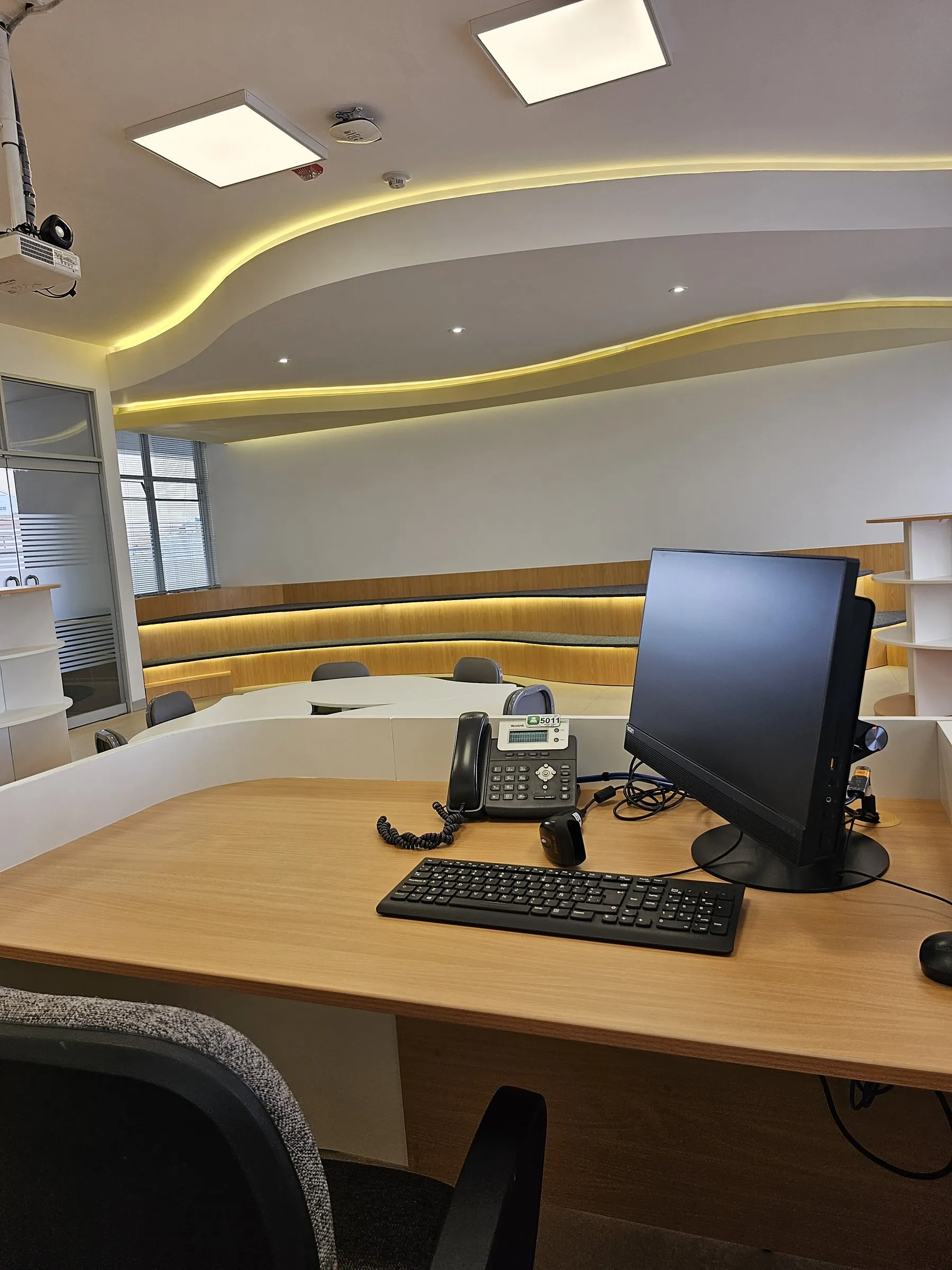 Puesto de trabajo con computadora y vista a la sala de lectura.